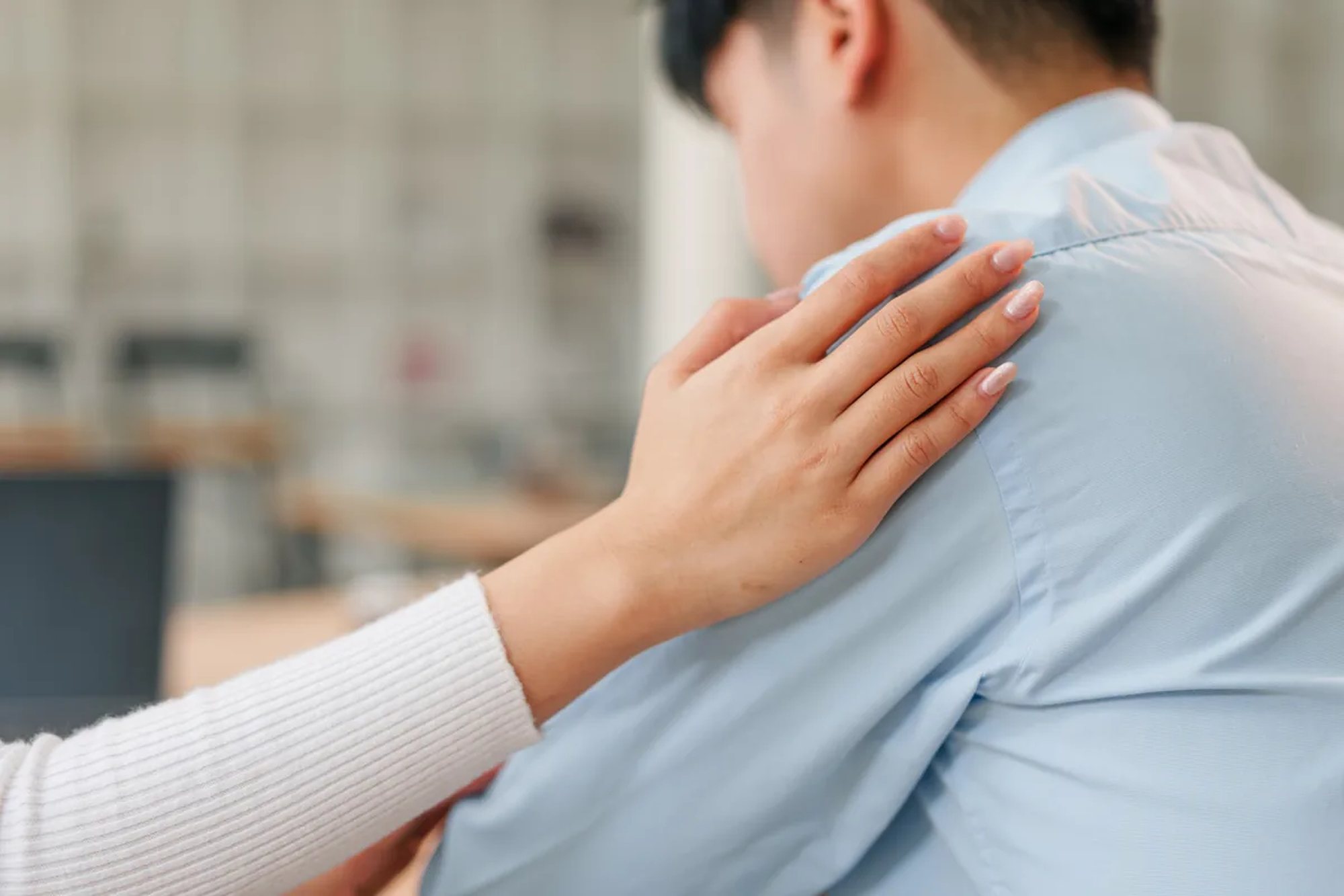 One person resting a hand on another's shoulder during a conversation